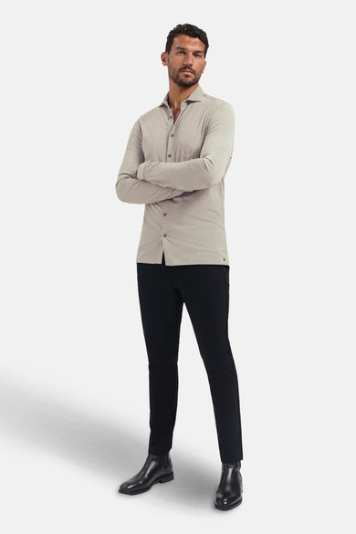 Chemise à manches longues beige de NO EXCESS, portée avec un pantalon noir et des bottines en cuir.