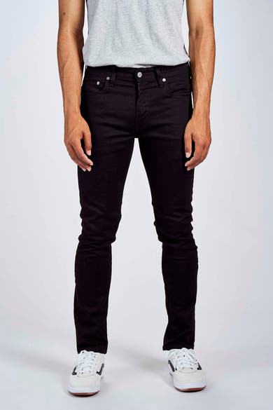 Jean fuselé noir de Levi's, porté avec un t-shirt gris et des baskets blanches.