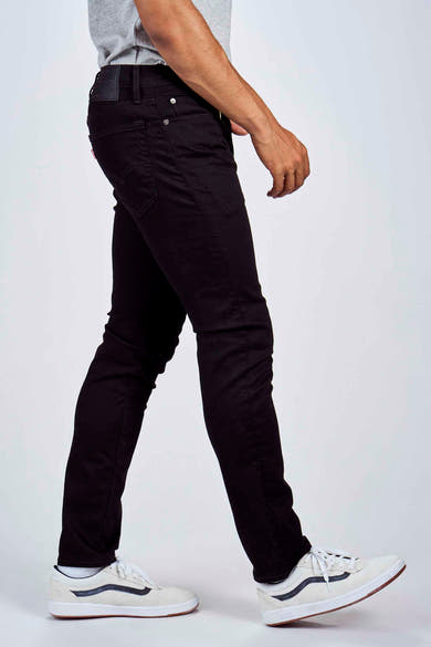 Jean fuselé noir de Levi's, porté avec un t-shirt gris et des chaussures de skate blanches.