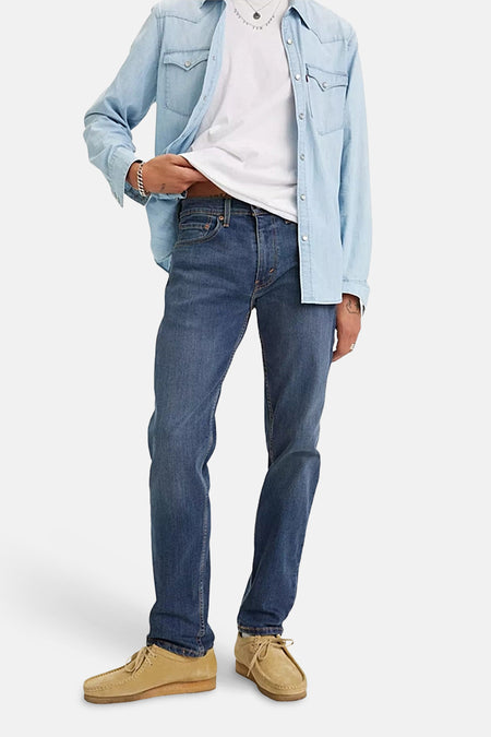 Jean fuselé bleu moyen de Levi's, porté avec une chemise décontractée et des chaussures en daim.