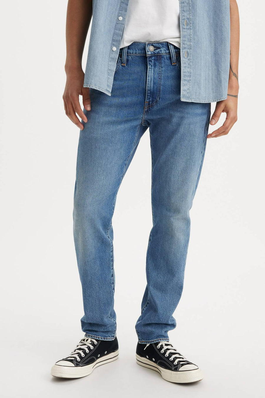 Taps toelopende spijkerbroek in middinblauw denim van Levi's, met achterzakken en gedragen met een effen wit T-shirt.