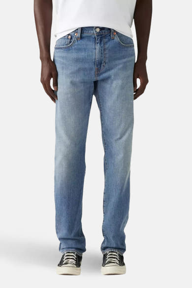 Jean fuselé bleu clair de Levi's, porté avec un t-shirt blanc et des baskets à motif.
