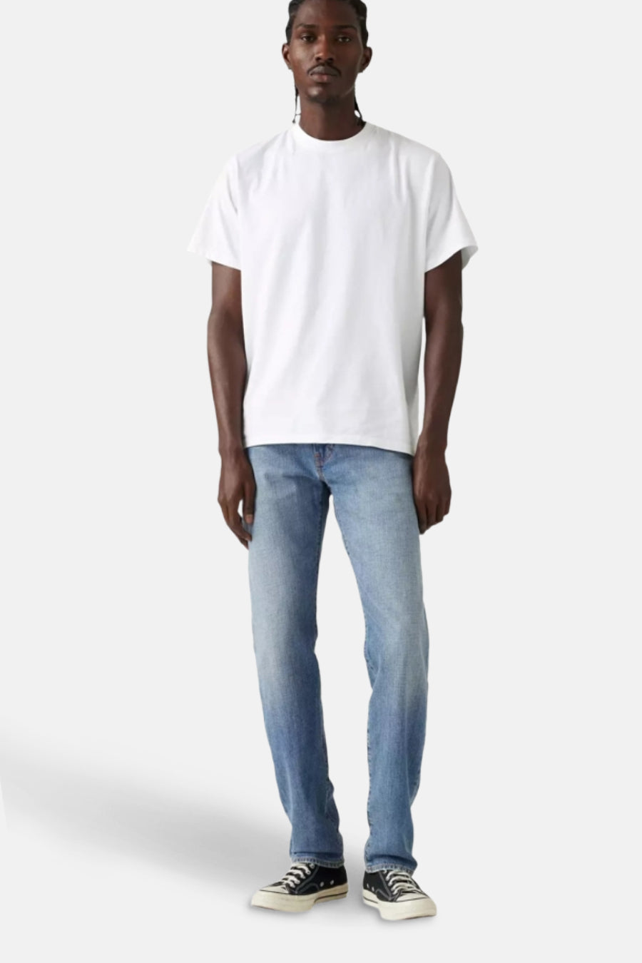 Jean fuselé bleu clair de Levi's®, porté avec un t-shirt blanc uni et des chaussures basses en toile.