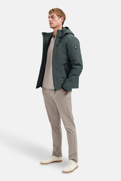 Groene regenjas van NO EXCESS met capuchon, gedragen met een beige broek en witte sneakers.