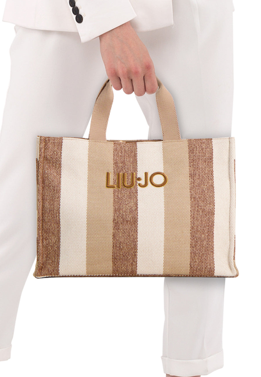 Ecru handtas van LIU JO, met bruine strepen en gouden logo, gedragen met een wit pak.