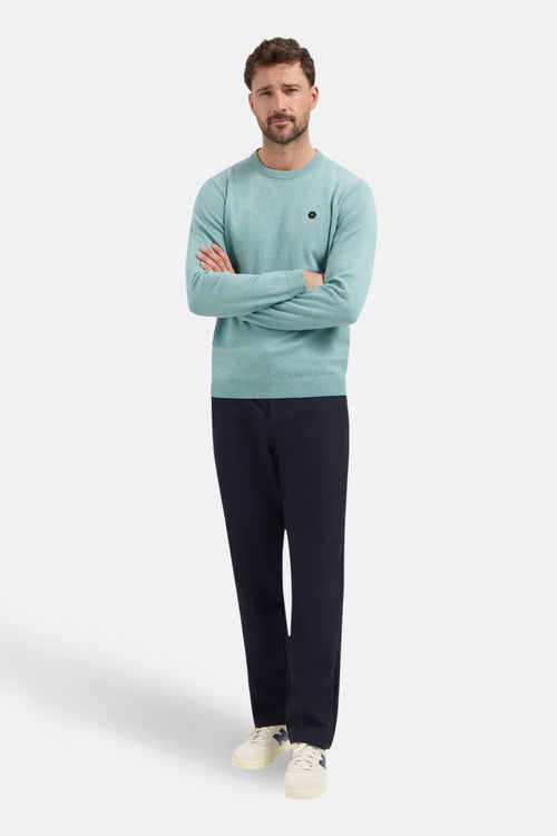 Pull à col rond bleu de NO EXCESS, porté avec un pantalon bleu marine et des baskets beiges.