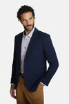 Blauwe blazer van DELAHAYE met een subtiele textuur, gedragen over een overhemd met geometrische patronen en zichtbare knopen op de mouwen.