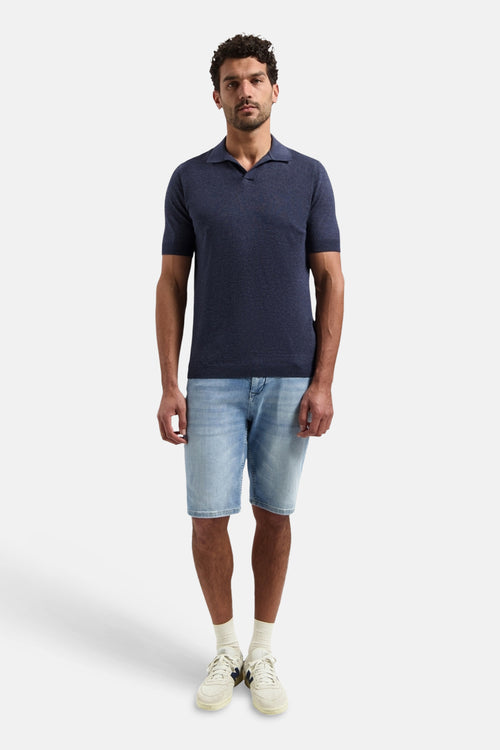 Pull bleu de NO EXCESS, porté avec un short en jean et des baskets blanches.