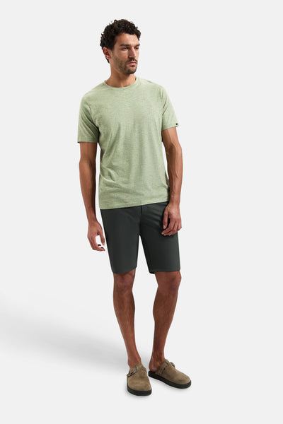 Groen T-shirt met korte mouwen van No Excess, gedragen met een korte broek en klompen.
