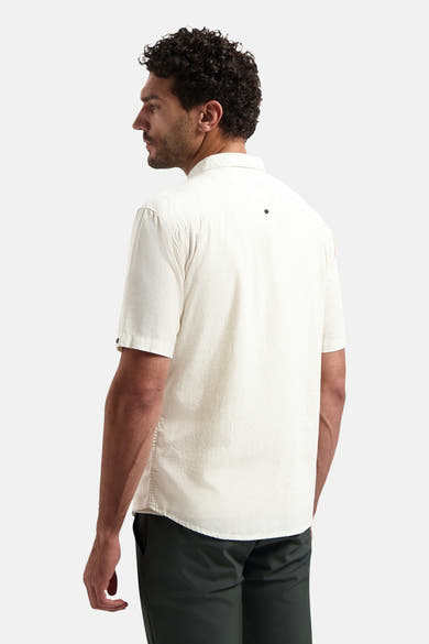 Ecru texturiseerd overhemd met korte mouwen van NO EXCESS, van achteren gezien, met een zwarte knoop op de kraag, gedragen met een donkere broek.