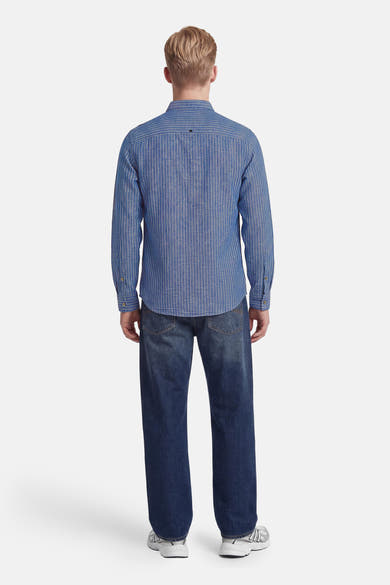 Chemise bleue à manches longues de NO EXCESS à fines rayures verticales blanches, vue de dos, portée avec un jean et des baskets.
