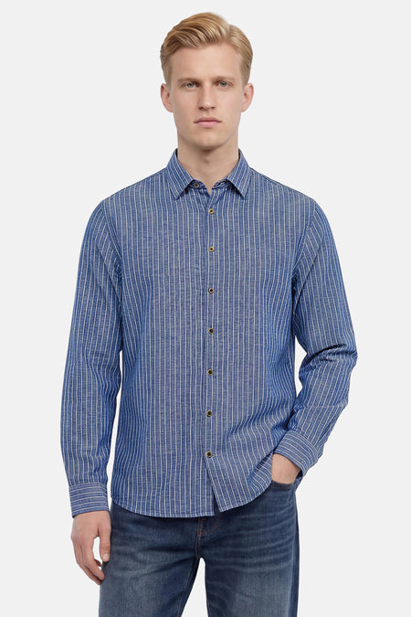 Chemise bleue à manches longues de NO EXCESS, à fines rayures verticales blanches et boutons dorés, portée avec un jean foncé.