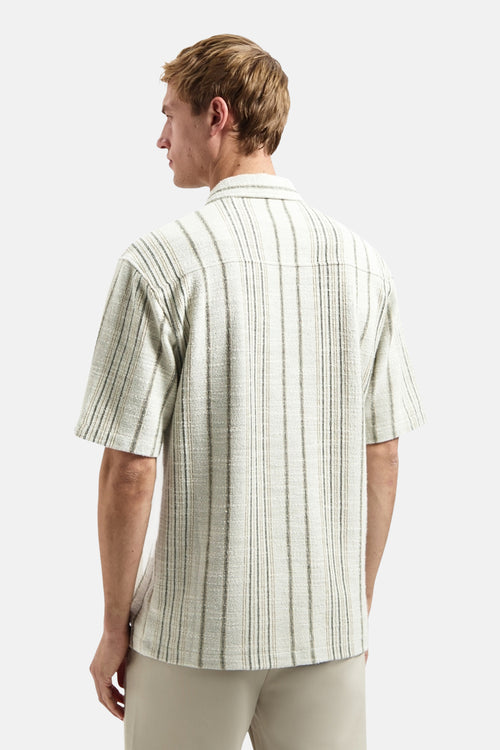 Chemise à manches courtes multicolore rayée, de NO EXCESS, avec une texture de tissu visible, portée de dos par un homme en pantalon beige.