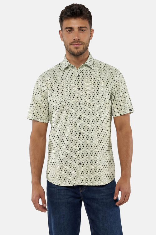 Chemise à manches courtes verte de NO EXCESS à motif hexagonal noir, portée par un homme avec un jean.