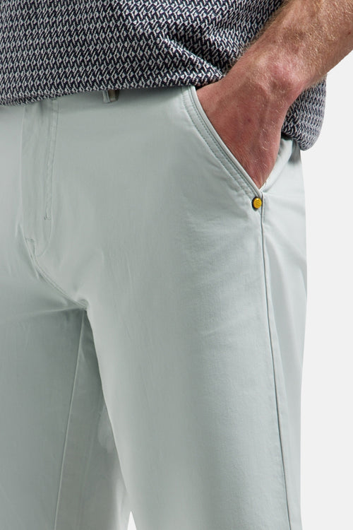 Short vert clair de NO EXCESS avec main dans la poche, bouton doré et chemise à motifs.