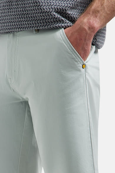 Short vert clair de NO EXCESS avec main dans la poche, bouton doré et chemise à motifs.