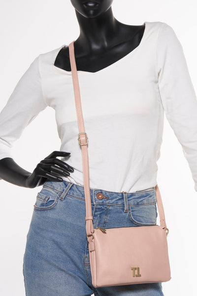 Roze schoudertas van TAMARIS, gedragen door een model met een spijkerbroek en een witte trui.