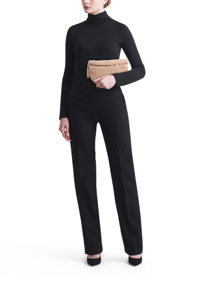 Sac à bandoulière beige de Tamaris, avec une texture douce et porté avec un pull noir à col roulé et un pantalon noir.
