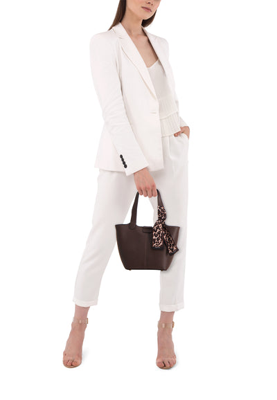 Sac à bandoulière marron de TAMARIS avec foulard à motif léopard, porté avec tailleur pantalon blanc et chaussures transparentes.