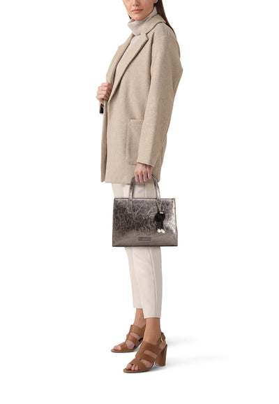 Sac à main gris de TAMARIS, avec motif craquelé et breloque décorative, porté avec un manteau beige et des chaussures à talons marron.