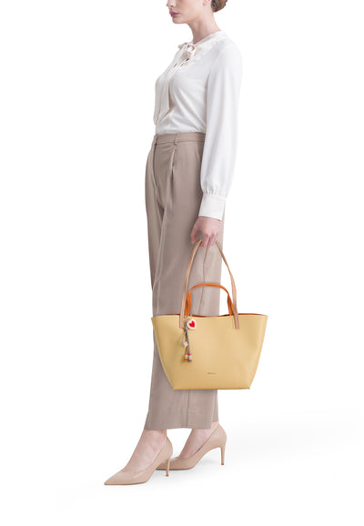 Sac à main jaune par TAMARIS, porté par une femme en pantalon beige et chemisier blanc.