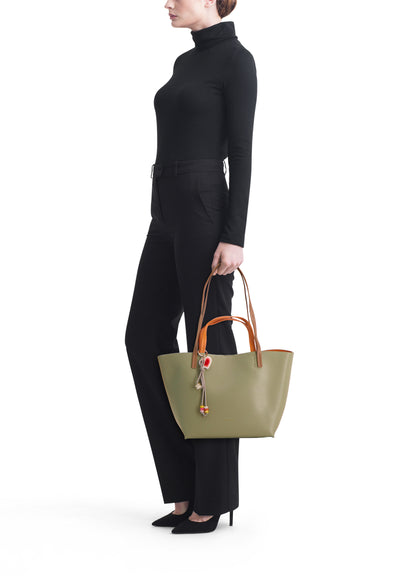 Sac à main vert de TAMARIS, porté par un mannequin en pantalon et pull noirs, vue de côté.