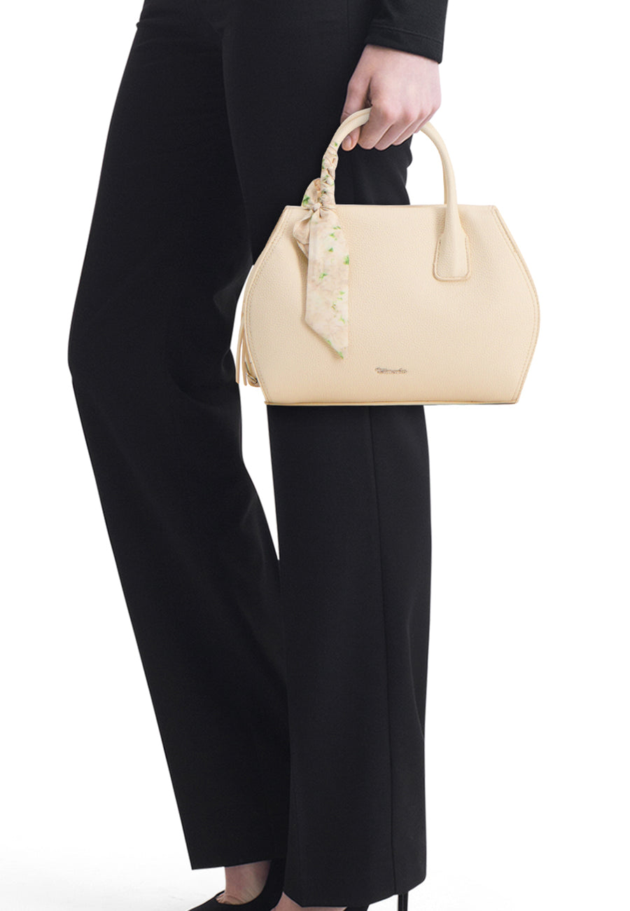 Sac à main jaune de TAMARIS, avec un foulard noué à la anse, porté avec un pantalon noir.
