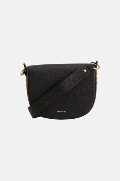 Zwarte leren handtas van TAMARIS, gedragen met een witte blouse en een beige broek met bijpassende hakken.