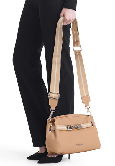 Sac à main beige de TAMARIS, avec bandoulière à rayures et fermeture à boucle argentée, porté avec un pantalon noir.
