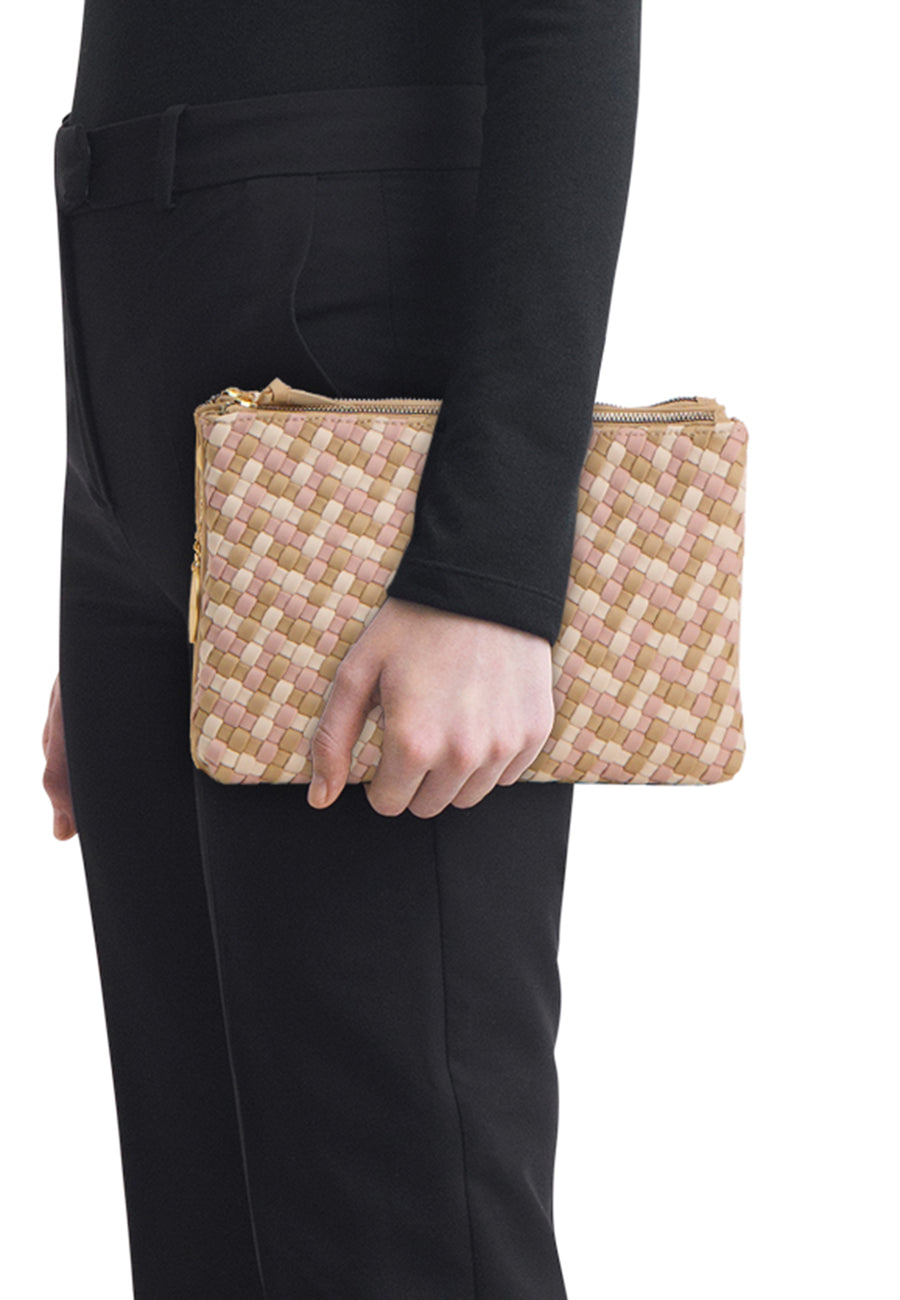Multikleuren gevlochten handtas van TAMARIS, met een patroon van roze en beige vierkanten en een gouden ritssluiting, vastgehouden door een persoon in het zwart.
