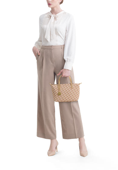 Petit sac à main tressé multicolore de TAMARIS, rose et beige, porté par une femme en chemisier et pantalon.
