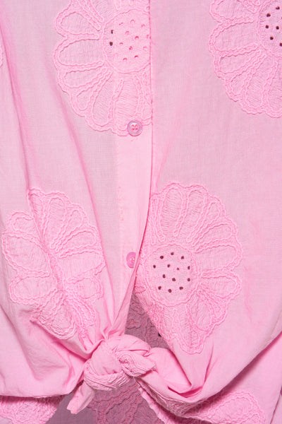 Chemisier rose à manches longues de Terra di Siena avec motifs floraux brodés et noué à la taille.
