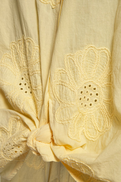 Chemisier à manches longues jaune de Terra di Siena avec broderie florale et détails ajourés.