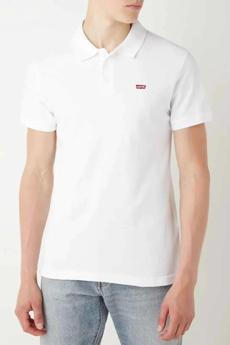 Polo blanc de Levi's, avec un petit logo rouge sur la poitrine, porté avec un jean décontracté.
