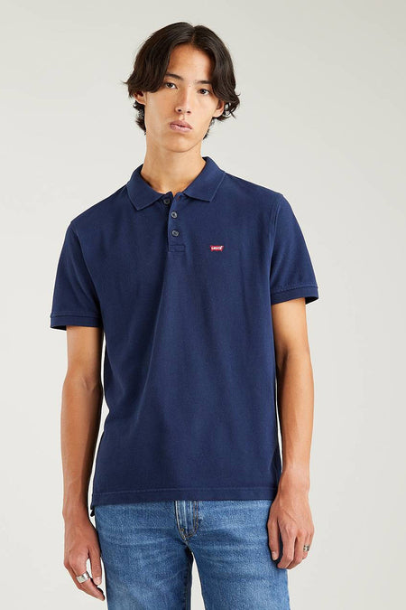 Polo bleu de Levi's, porté avec un jean bleu et des anneaux en argent.