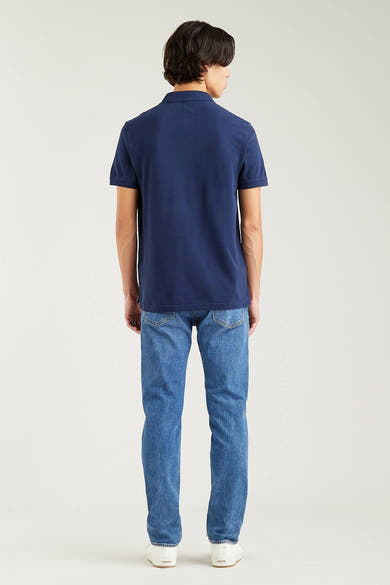 Polo bleu par Levi's, porté avec un jean décontracté et des chaussures de sport blanches, vue de dos.