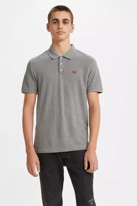 Polo gris à manches courtes de Levi's, avec logo rouge sur la poitrine, porté avec un jean noir délavé.
