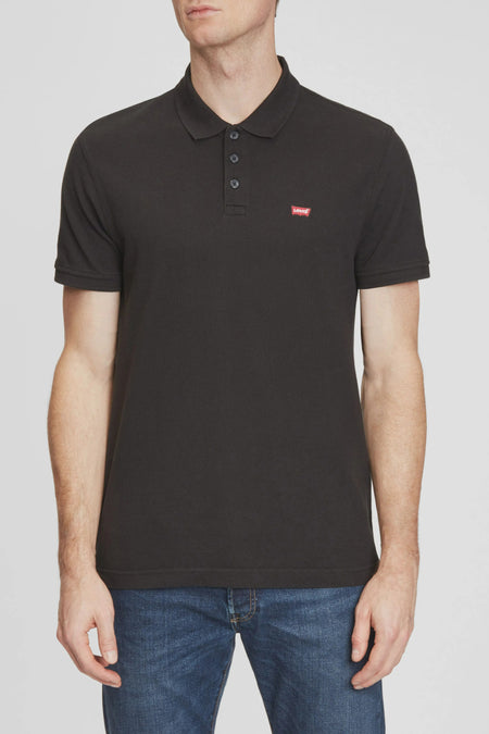 Polo à manches courtes noir de Levi's, avec un logo rouge distinctif, porté avec un jean bleu.
