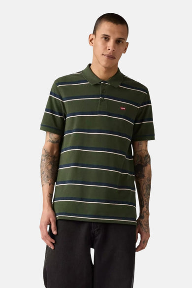 Polo à manches courtes vert rayé de Levi's®, avec logo rouge sur la poitrine et porté avec un pantalon noir.
