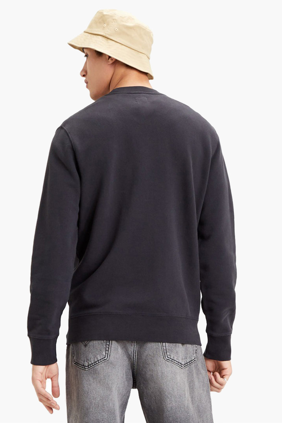 Sweat noir de Levi's, vu de dos, porté avec un bob beige et un jean gris.