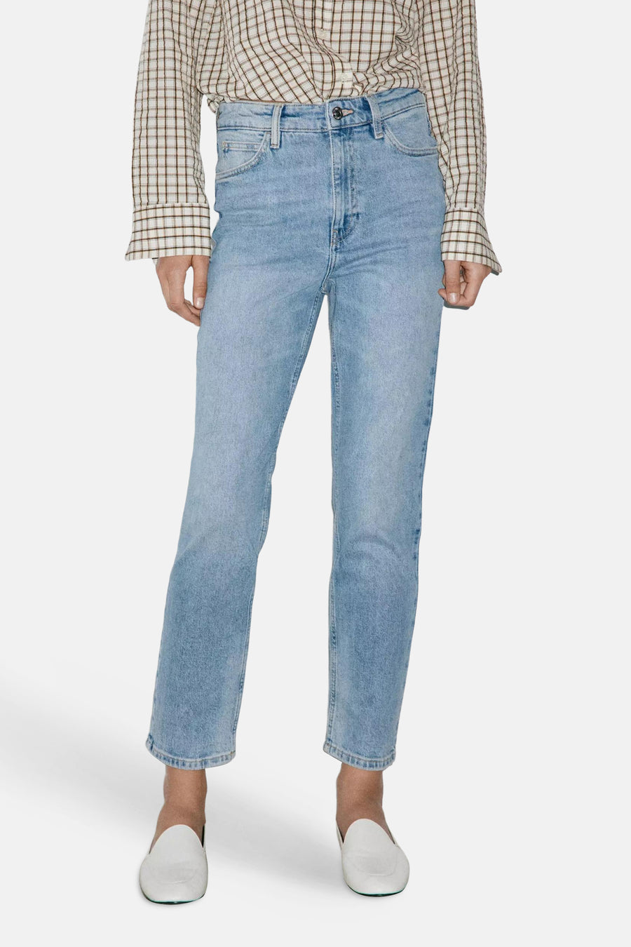 Light blue high-rise mom jeans by NEWMOM, featuring faded wash, straight leg cut, and classic five-pocket styling, worn with plaid shirt and white loafers.