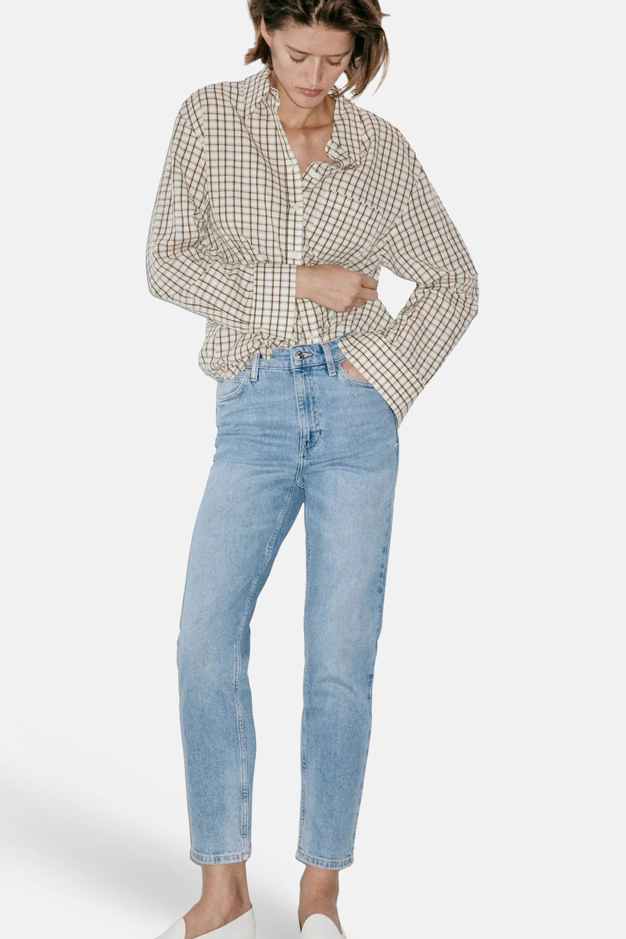 Light blue mom jeans by NEWMOM, featuring a high waist, straight leg, and faded denim texture, styled with a plaid shirt and white shoes.