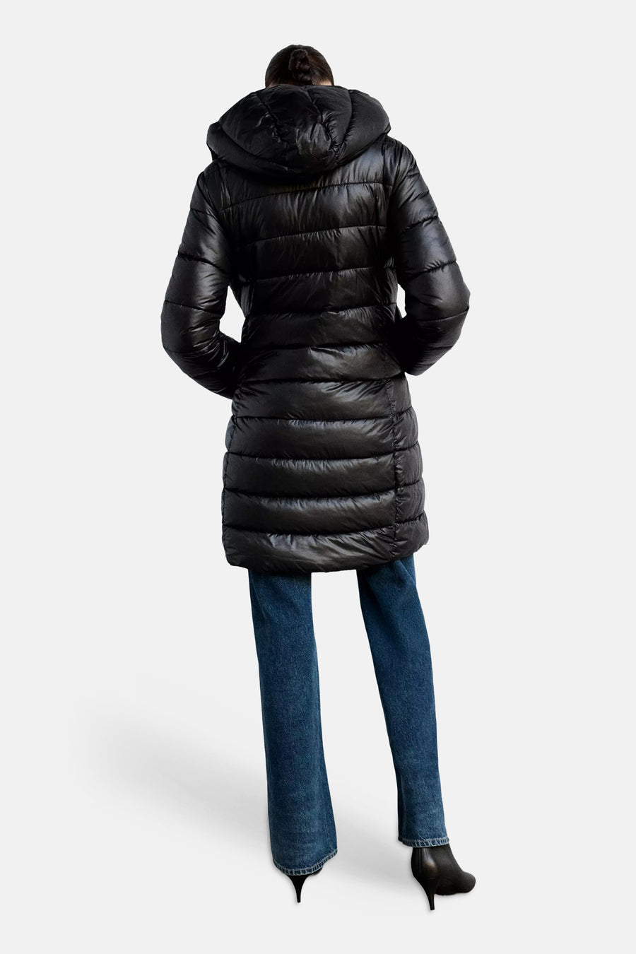 Black quilted puffer coat with hood, back view, worn with blue jeans and black heels
