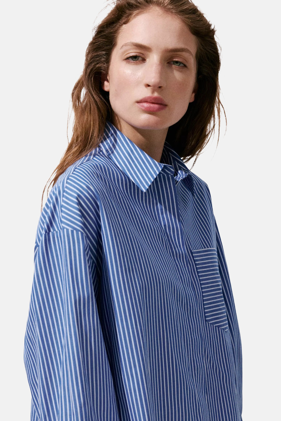 Blue and white striped long-sleeve blouse with pointed collar and chest pocket, side view on model