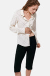 Cream long-sleeve blouse with black grid pattern, worn open over black cropped pants, side view.