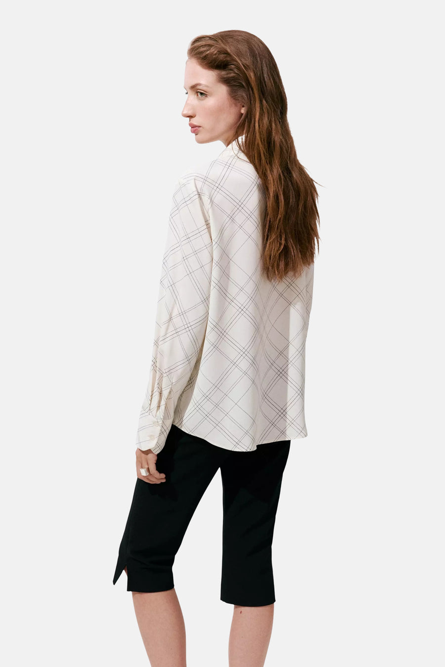 Cream long-sleeve blouse with black grid pattern, side view, worn with black cropped pants
