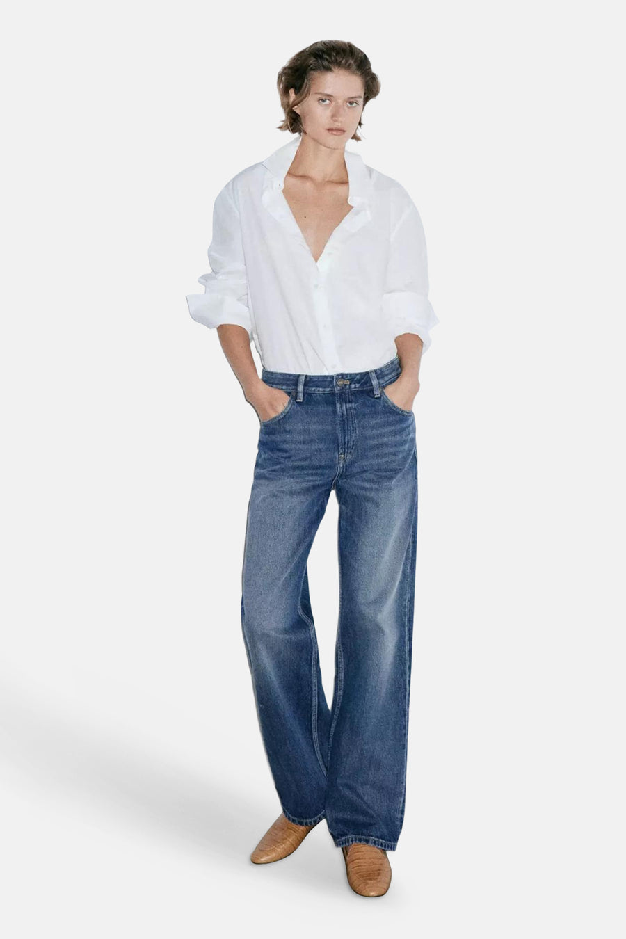 Dark blue straight-leg denim jeans with faded wash and relaxed fit, worn with white shirt and brown boots, front view.