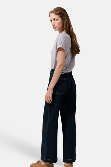 Dark blue wide-leg denim jeans by CATHERIN, side view, with cuffed hems and classic back pockets, worn with a gray t-shirt and brown loafers