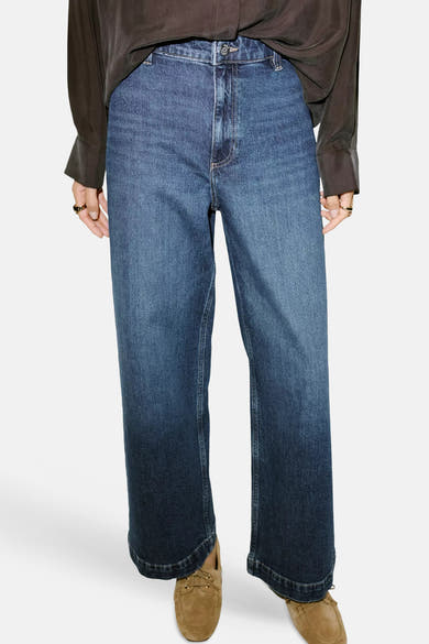 Dark blue wide-leg denim jeans by CATHERIN, front view with cuffed hems and classic stitching, worn with brown top and tan loafers