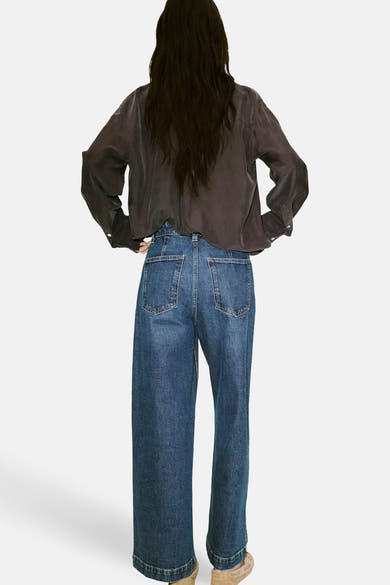 Dark blue wide-leg denim jeans by CATHERIN, back view, featuring classic stitching and two patch pockets, worn with a dark satin shirt.